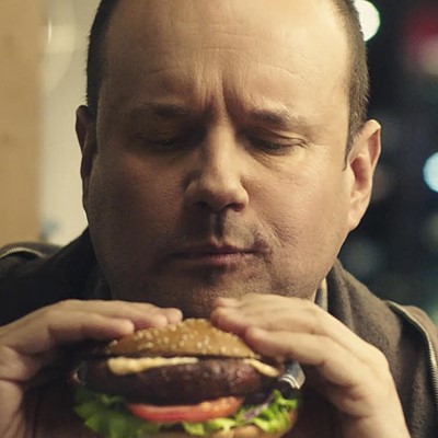 Man i närbild som äter hamburgare. Foto från reklamfilm. 